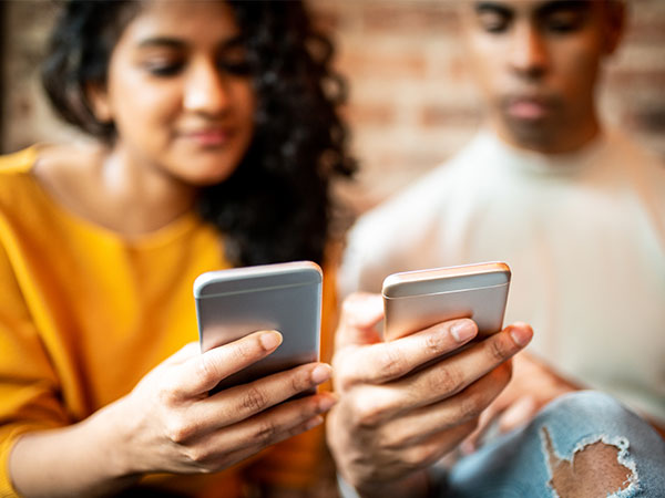 Two friends exchanging money through mobile phones