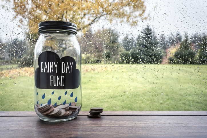 Savings for a rainy day fund in a glass jar of money.